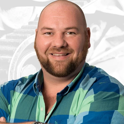 Sebastian Rahmfeld lächelt in einem gestreiften Hemd mit grün-blauen Farbtönen.